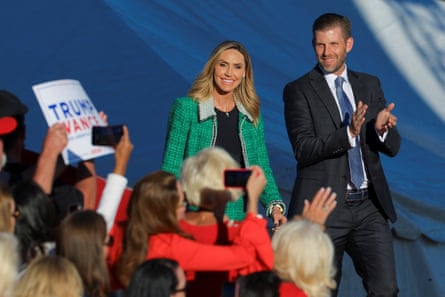 a woman and a man smile while walking on stage in front of a crowd of people