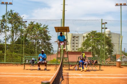 Charles Wanyama, an umpire during the Uganda National Tennis Champions (UNTC), looks down on Simon Ayera, left, during a water break in a quarter-finals match. Ayera’s opponent Godfrey Ocen sits on the right at Kampala Tennis Club, 15 May 2022.