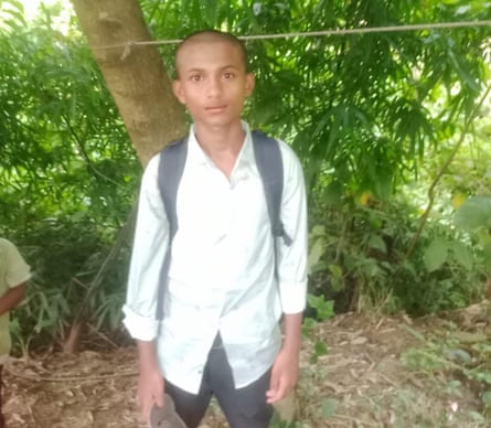 A boy in a white shirt and with a small rucksack on his back staring at the camera