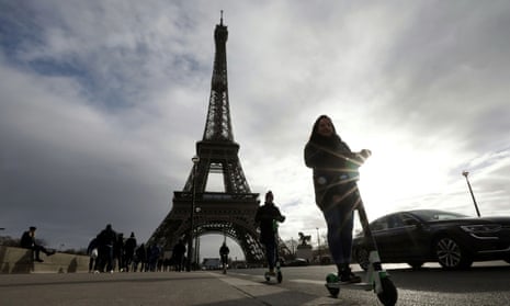 People ride dock-free electric scooters near the Eiffel tower.
