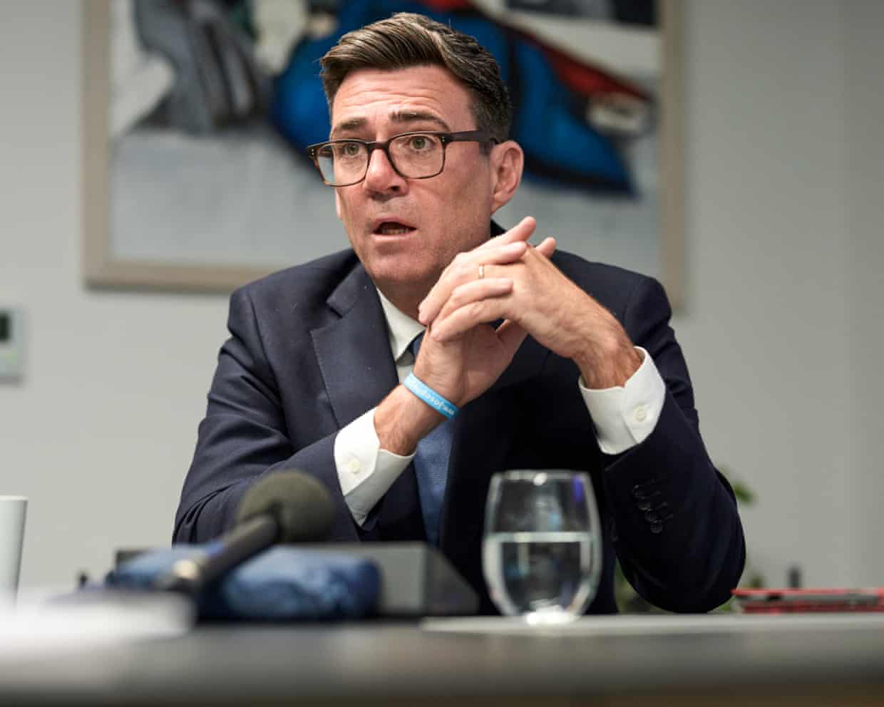 Burnham speaking at desk with glass of water in front of him