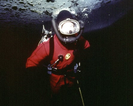 A person in a diving suit just under the surface of the water