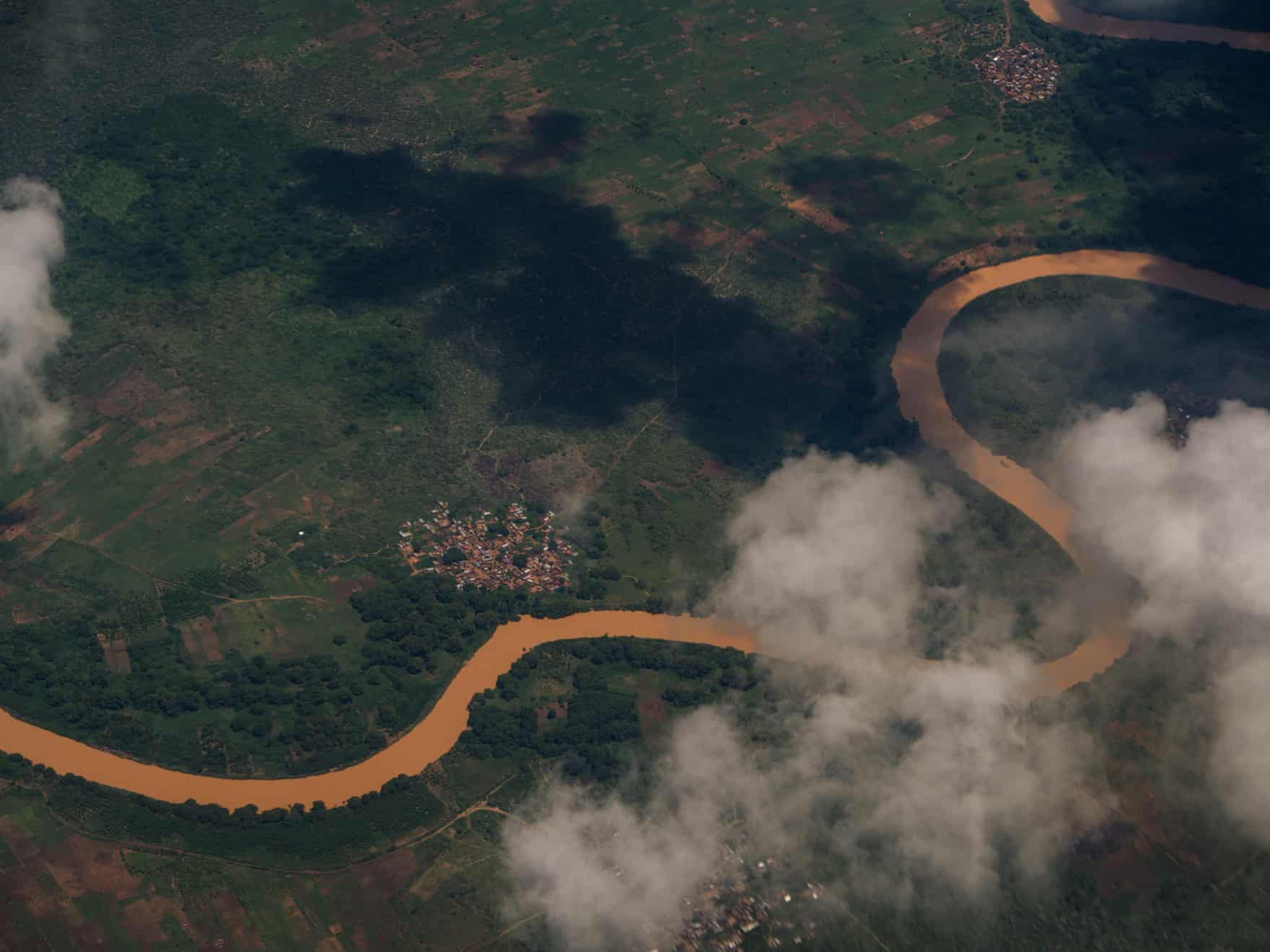 Aerial view of the Jubba river winding through green farmland near Kismayo, partly obscured by clouds