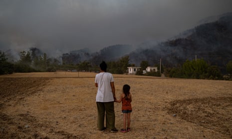 A woman and a girl hold hands while watching wildfires burning in Köyceğiz district in Turkey in 2021. 
