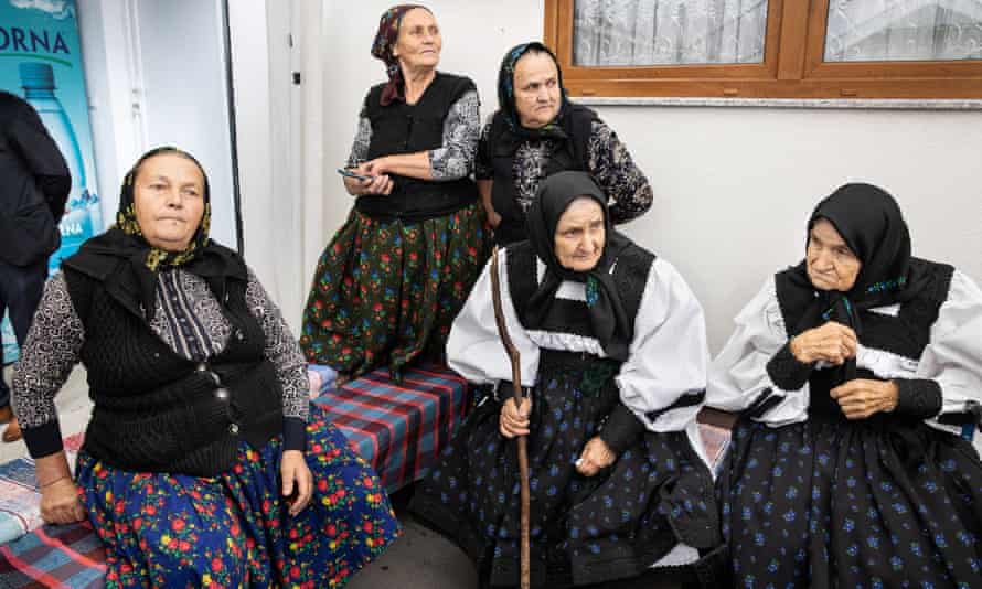 Women in traditional costumes watch dancing guests during the wedding of Mihai Big and Denisa Avram in Racsa village.