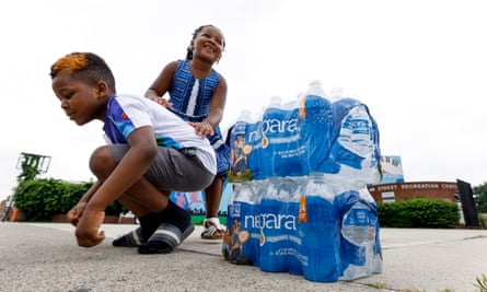 Children play next to packages of bottled water at a city-run water distribution site in Newark, New Jersey, on 16 August.