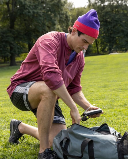 Paul Anthony Kelly as JFK holding a Walkman while kneeling over a bag