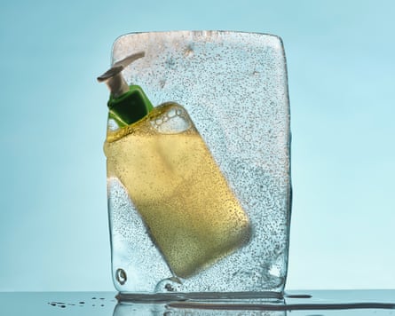 Still life of a cleanser bottle encased in an ice cube