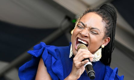 Allison Russell singing into a microphone, on stage in a blue top