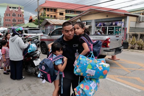 A man carries two schoolgirls to safety outside a Thailand school shooting site
