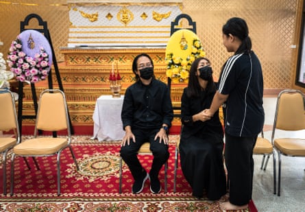 The parents of 12-year-old school shooting victim Naphat Chaima sit in front of her casket during her funeral at the Wat Lat Pla Duk Buddhist temple in Nonthaburi province.