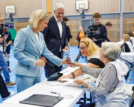 Magdalena Andersson shows her passport to election officials at a polling station in a gym