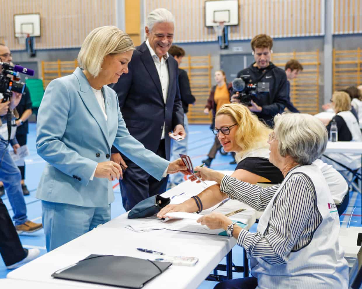 Magdalena Andersson shows her passport to election officials at a polling station in a gym