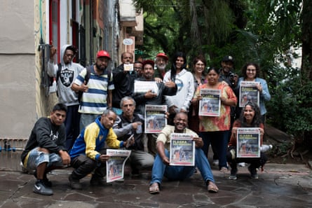 The team behind Boca de Rua pose for a group photo while holding copies of the paper, in Porto Alegre