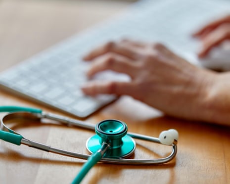 Close up view of hands on a keyboard and a stethoscope on a table