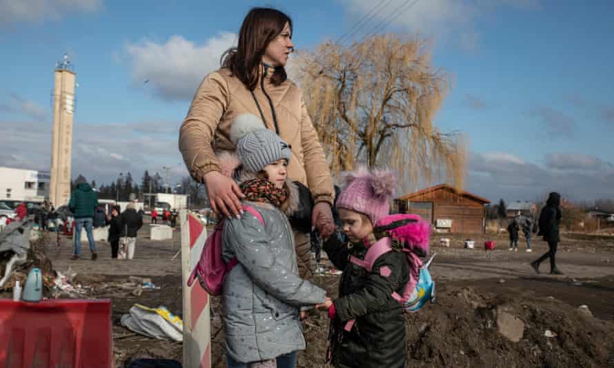 A woman and her two children holding hands.