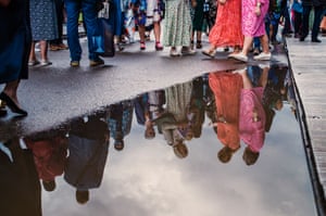 Reflection of people walking around puddle.