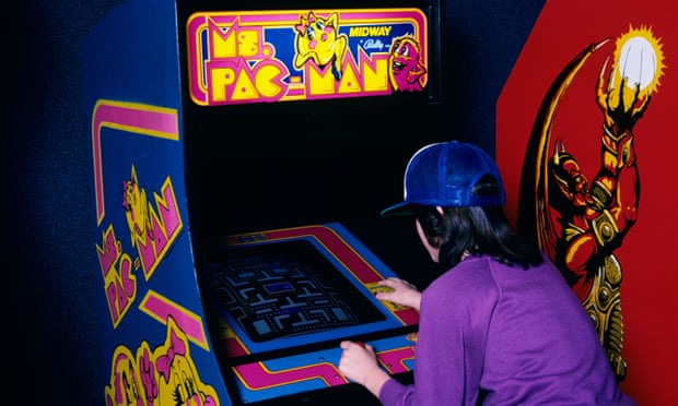 A teenager playing Pac Man in an arcade in the 1980s.