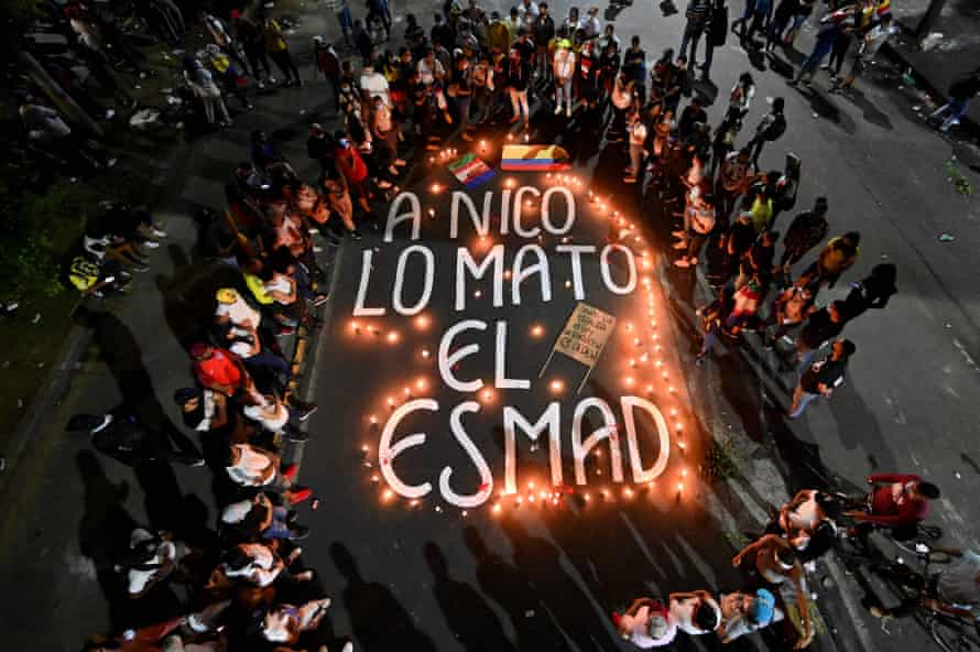 Overhead shot of relatives and friends of Nicolás Guerrero gather around candles surrounding the words “Nico was killed by Esmad