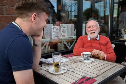Two men sitting opposite each other at a table outside a restaurant