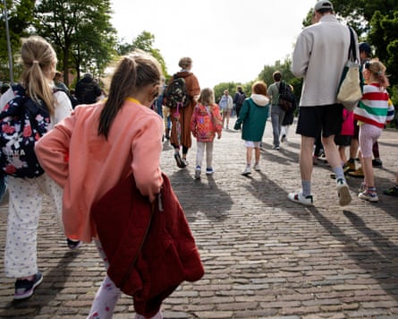 Children and parents walk along a cobble street