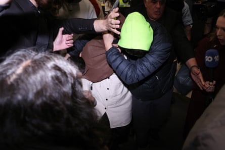 One of the returning women is shielded by supporters at Melbourne airport.