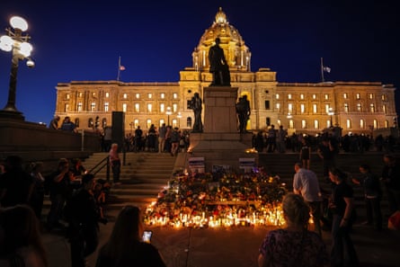 people stand around candlelit memorial outside of capitol building at night