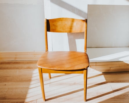 A wooden chair in sunbeams inside an empty house