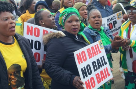 Protesters demonstrate outside the court holding up signs that read ‘No bail’