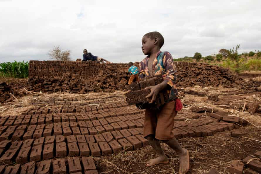 A young boy carries bricks to a kiln, to earn money in Chitukula, Lilongwe, Malawi.