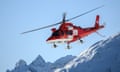 A helicopter from the Swiss Air-Rescue REGA flies above mountains