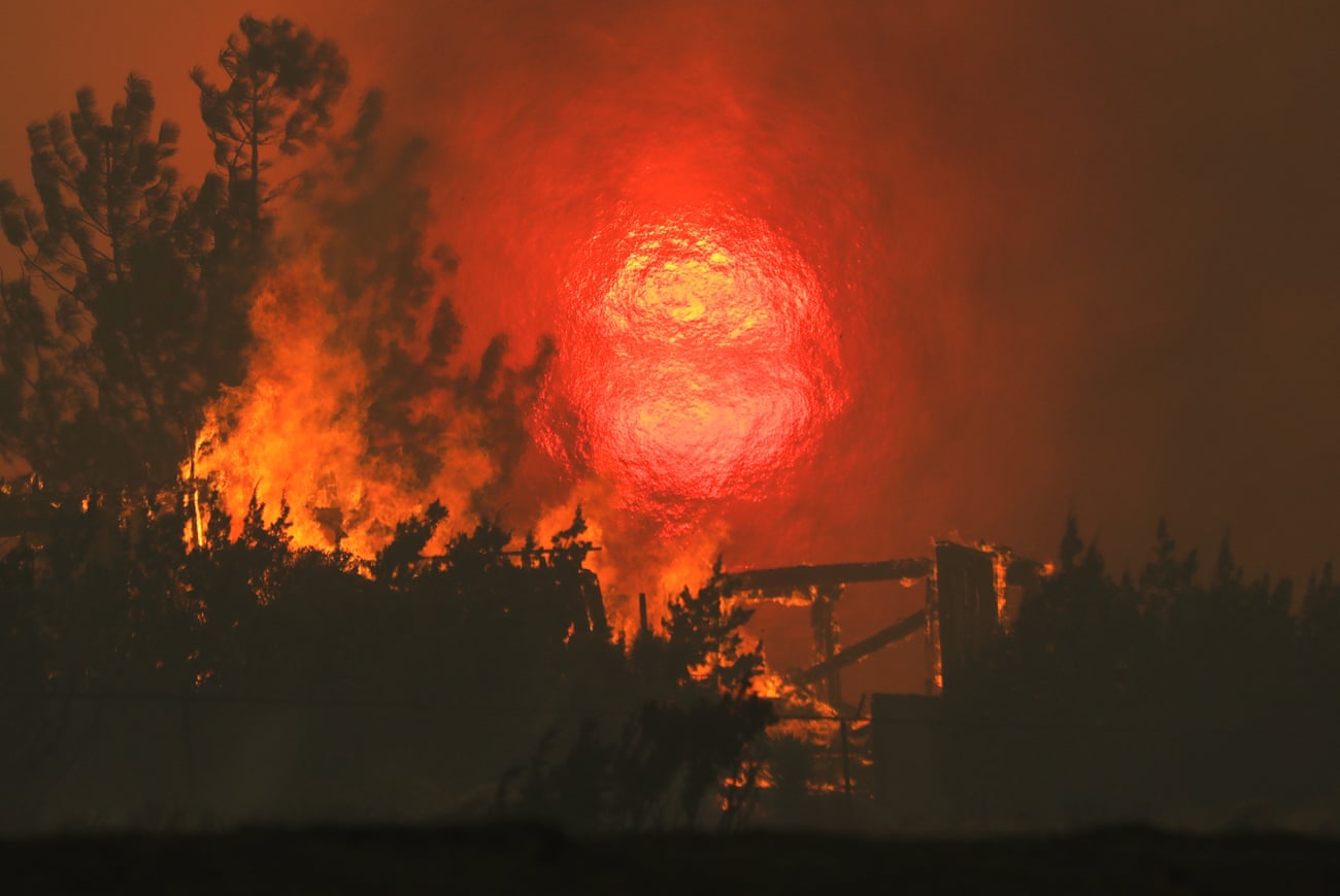 A home burns as the sun sets behind smoke and flames during the Bobcat fire in Juniper Hills, California, on Friday.