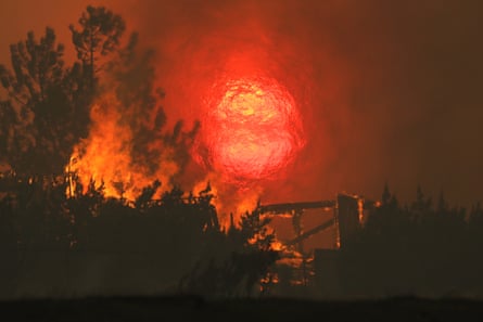 A home burns as the sun sets behind smoke and flames during the Bobcat fire in Juniper Hills, California, on Friday.