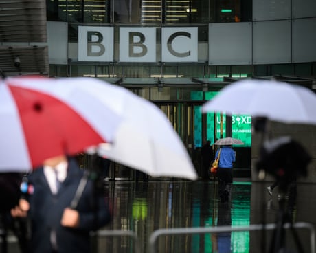 people outside a building with umbrellas