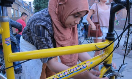 An asylum seeker works on her bike.