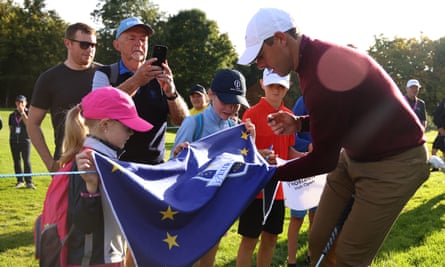 Rory McIlroy signs a Ryder Cup Europe flag for young fans.