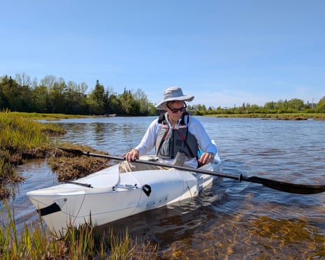 man in hat and sunglasses sits in kayak on river