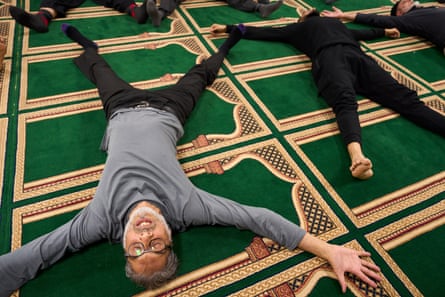 Instructor Zafar Kayani (in grey top) lies on the mosque carpet with his arms and legs outstretched