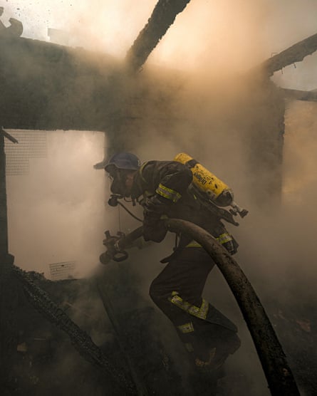 A Ukrainian firefighter sprays water inside a house destroyed by shelling in Kyiv