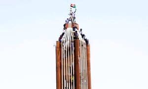 Demonstrators fly their national flag on a building near the defence ministry in Khartoum