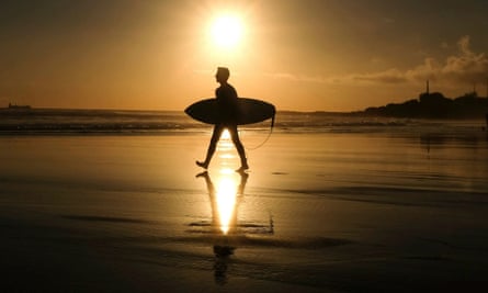 A surfer goes to the water at Carcavelos beach in Portugal.