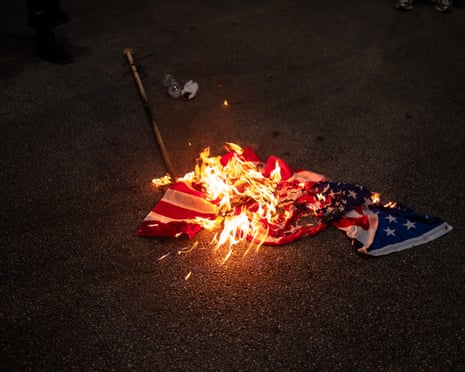 An American flag being burned in the street near where the Democratic national convention is being held on 22 August 2024 in Chicago, Illinois.