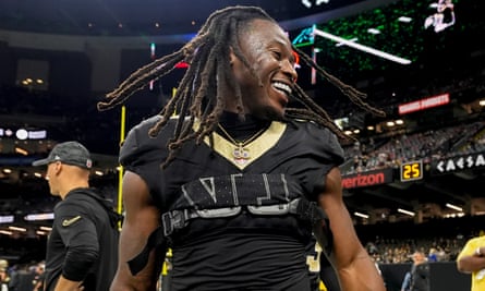 Alvin Kamara smiles with friends on the touchline before the game