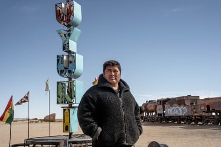 A man stands in front of a sign reading ‘Uyumi’ and an old train