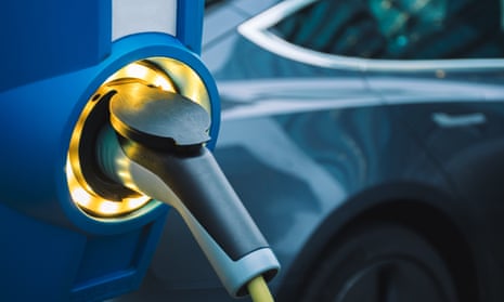 Electric car charging with EV in background.