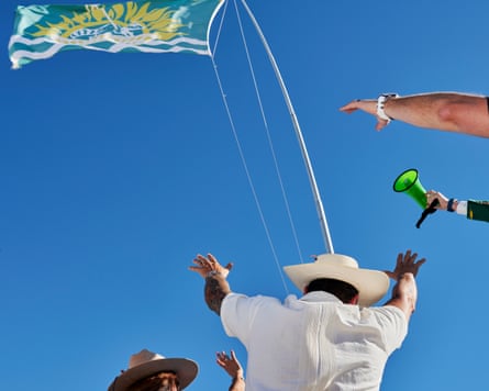 people with arms raised under a green flag