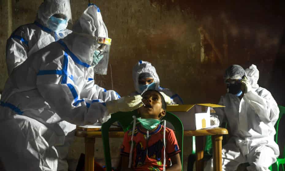 A health worker (L) collects a swab to carry out a coronavirus test on a boy in Kolkata. There were nearly 50,000 new cases recorded in India.