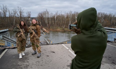 The girlfriends of Ukrainian soldiers pose for a photo on a destroyed bridge in Bohorodychne, Ukraine.