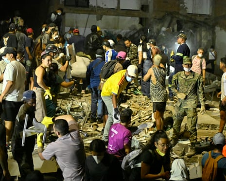People and rescuers search for victims amid debris of a collapsed seven-story building at Plaza Bolivar in Pereira, Colombia