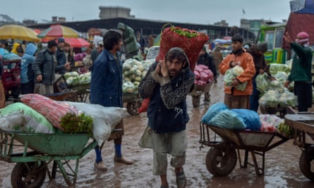Traders and labourers work during a rainy day at a vegetable market in Peshawar